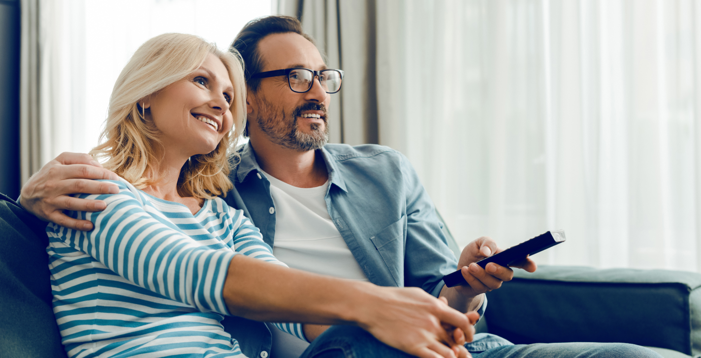 Couple regarde la télévision avec leurs appareils auditifs Bluetooth