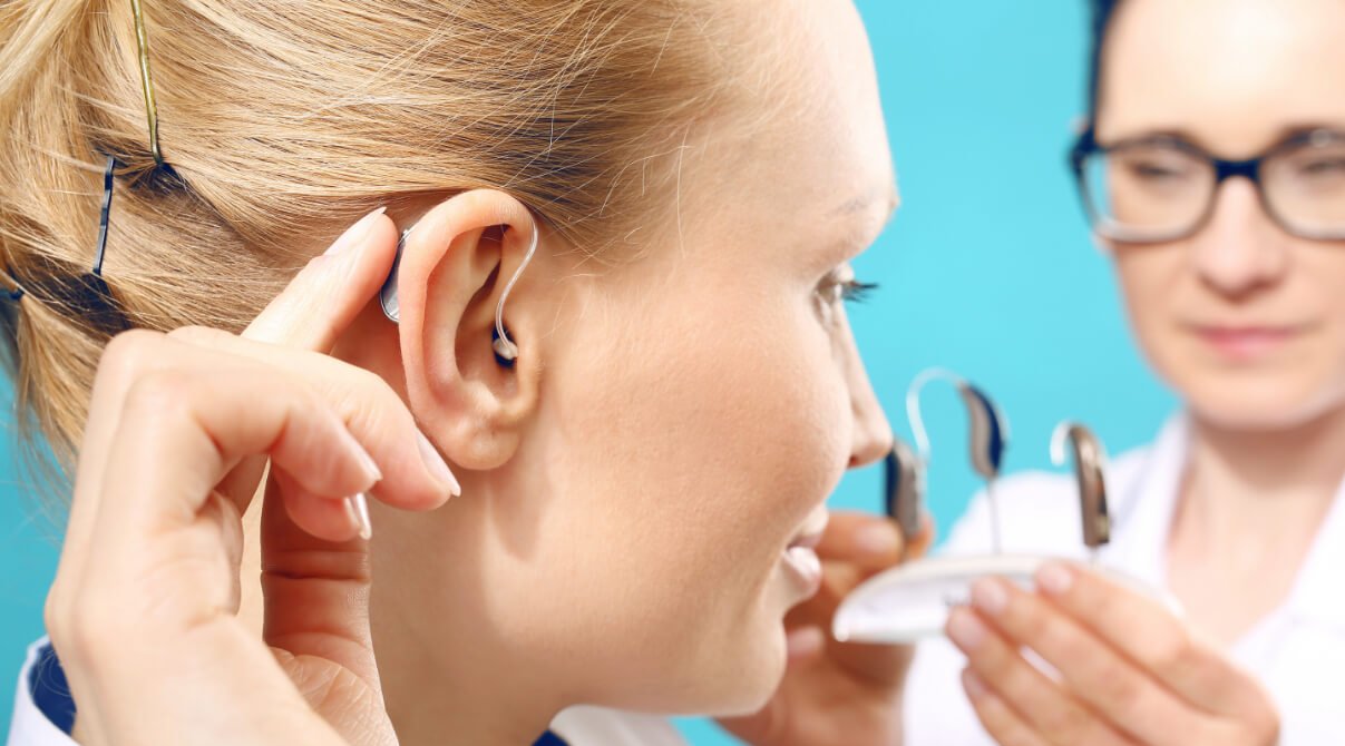 Audioprothésiste fait essayer un appareil auditif contour d'oreille