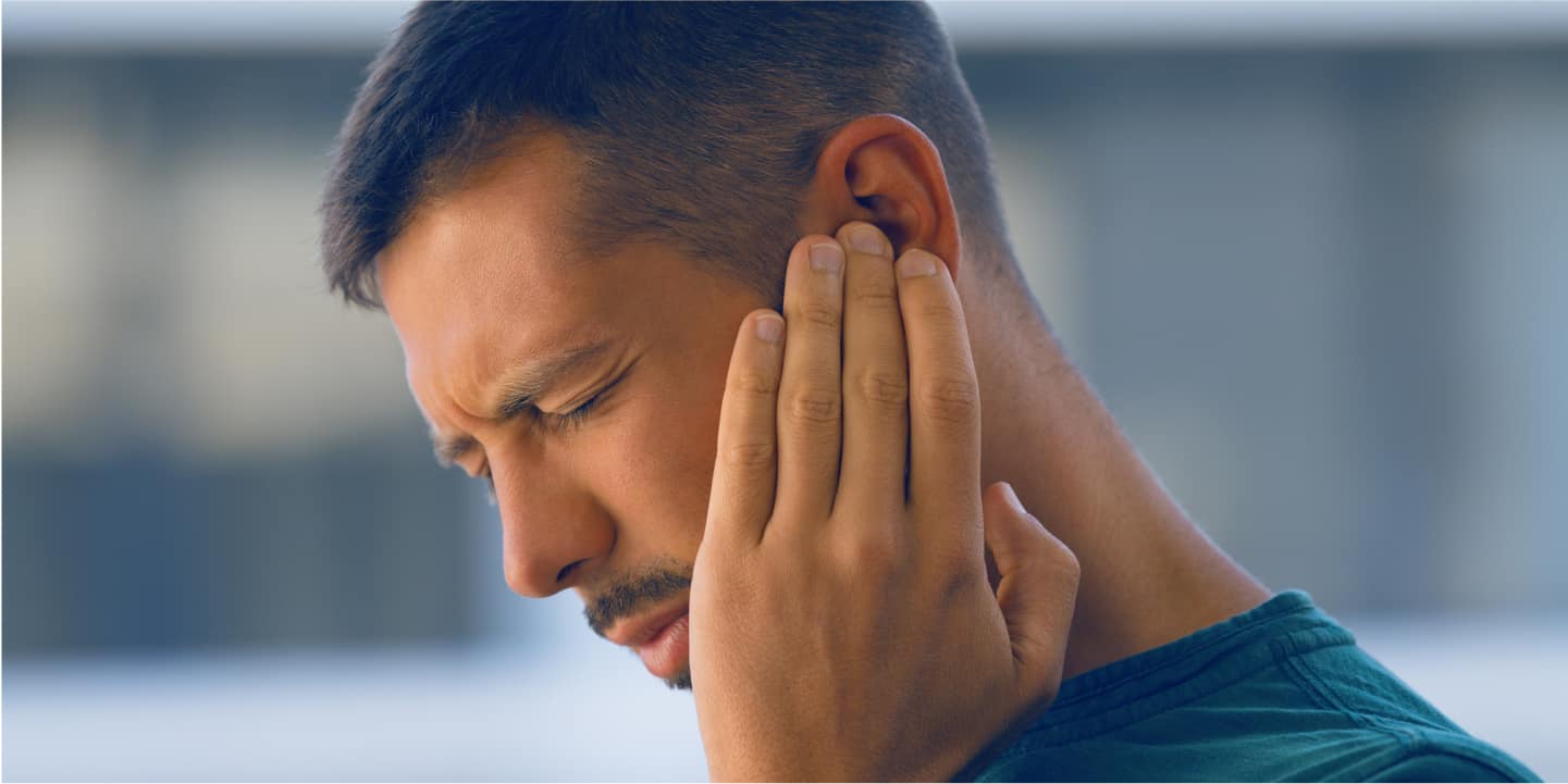 jeune homme se tient l'oreille à cause des acouphènes