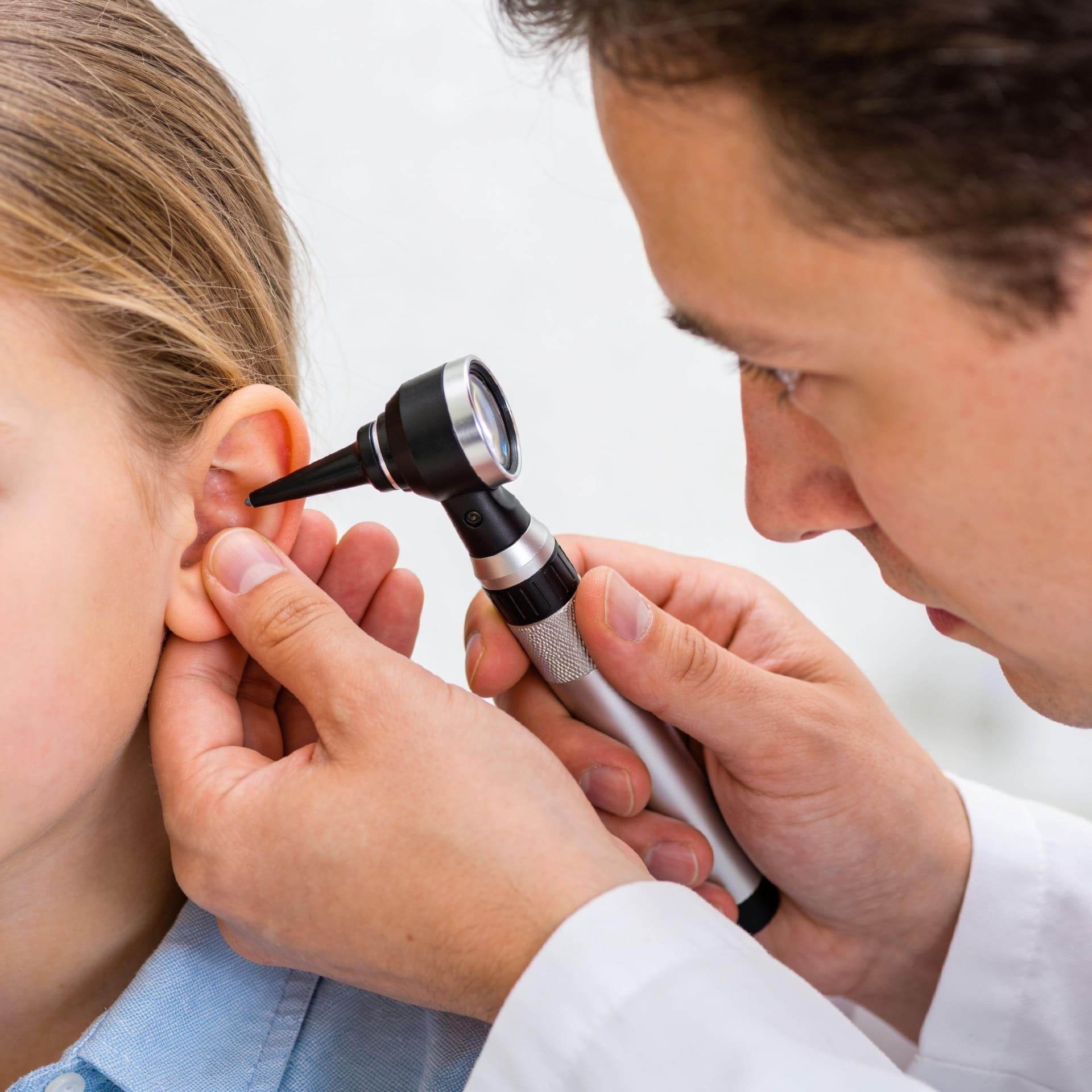 Médecin ORL examinant l’oreille d’un enfant avec un otoscope lors d’un diagnostic d’otite moyenne aiguë